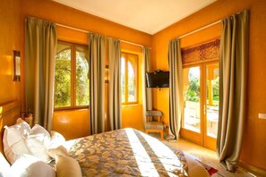 A hotel room with a bed, a television, and a view of the outdoors. - Villa Hana Marrakech, with views of the Atlas Mountains, nestled in a 1 ha park. (Sidi Abdellah Ghiat)