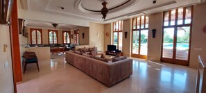 A spacious living room with a large L-shaped sofa, a television, and a dining area with a table and chairs. - Villa Hana Marrakech, with views of the Atlas Mountains, nestled in a 1 ha park. (Sidi Abdellah Ghiat)