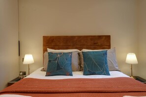 Ein Hotelzimmer mit einem Bett, zwei Nachttischlampen und einer roten Decke.