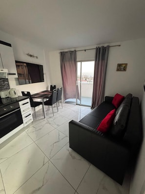 A modern living area with a sofa, dining table, and kitchen. - Sea view modern apartment in Las Americas (Costa Adeje)