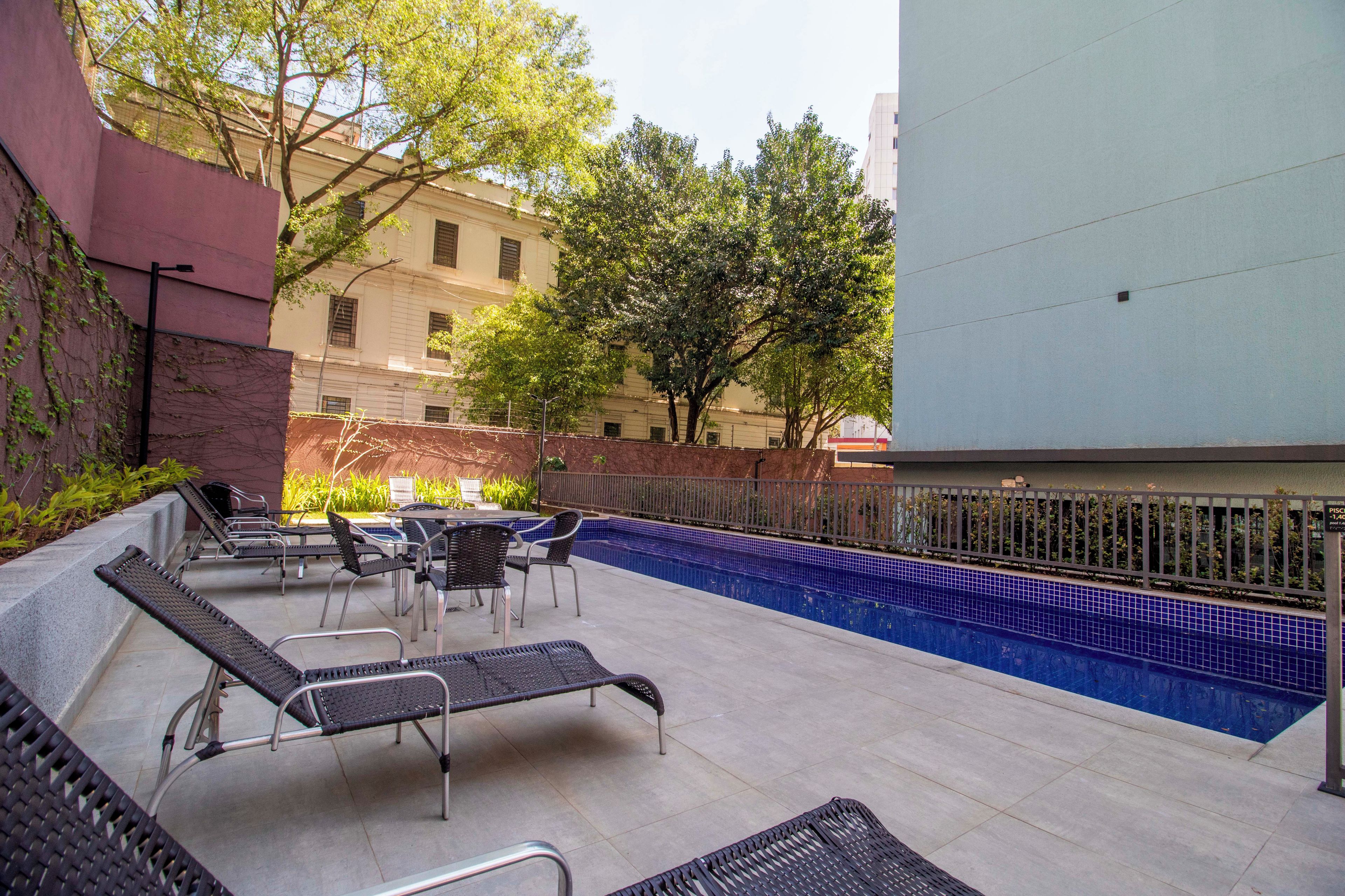 An outdoor swimming pool area with lounge chairs and a table.