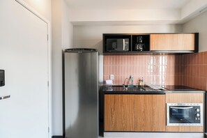 Cuina compacta amb nevera, microones, cafetera, rentatallera i forn encastrat.