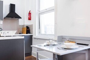 Eine moderne Küche mit einer zentralen Kochinsel, einer schwarzen Dunstabzugshaube und einem Fenster für natürliches Licht.