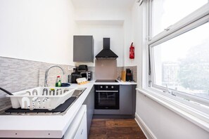 Eine kleine Küche mit Gasherd, Backofen und einem Fenster mit Blick auf die Stadt.