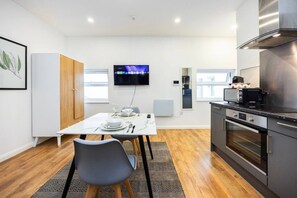Eine moderne Küche mit Essbereich, Flachbildfernseher und Backofen.