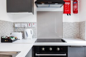 Une cuisine moderne équipée d’un four encastré, d’un espace dédié à la préparation du café et d’un extincteur.