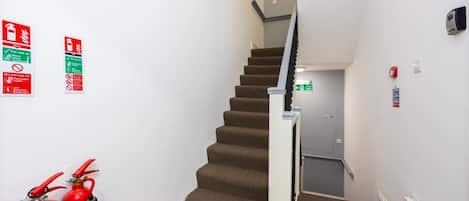 A staircase with fire extinguishers and emergency exit signs.