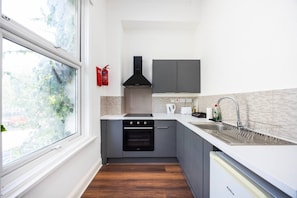 A compact kitchen with a stove, oven, and modern sink. - Earl`s Court Residence | Stylish Studio | London (Greater London)