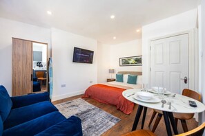 A modern bedroom with a bed, bedside table, and a TV mounted on the wall. - Earl`s Court Residence | Elegant Studio | London (Greater London)