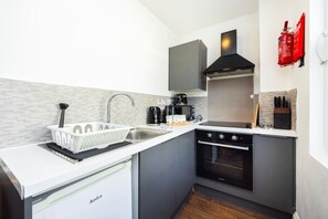 A compact kitchen with a sink, stove, and a coffee maker. - Earl`s Court Residence | Elegant Studio | London (Greater London)