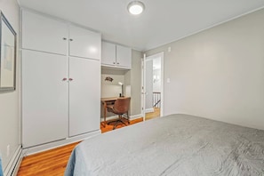 A bedroom with a large bed, a wardrobe, a desk with a chair, and a staircase leading to an upper level. - Walk to Saratoga Track | 2 Kings | Pet OK (Saratoga Springs)