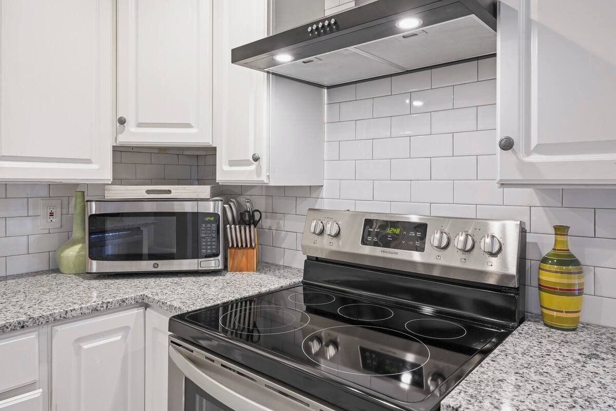 A kitchen with white cabinets, a microwave, a stove, and a set of knives on the counter.