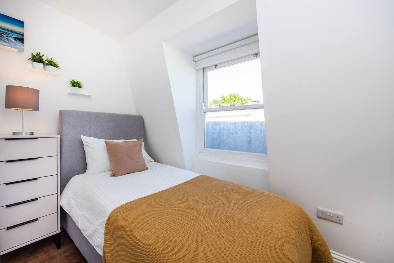 Une chambre à coucher avec un lit, une table de chevet, une lampe et une fenêtre donnant sur un beau paysage.