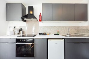 A modern kitchen with grey cabinets, a black range hood, a dishwasher, and a sink. - Earl`s Court Residence | Stylish 2BR | London (Greater London)