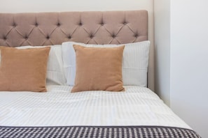 Ein Bett mit einer gebügelten Kopfteil, zwei Kissen und einer gestreiften Bettdecke.