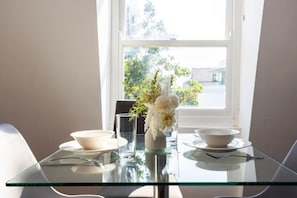 A dining table with two bowls, a glass, and a vase with flowers. - Earl`s Court Residence | Stylish 2BR | London (Greater London)