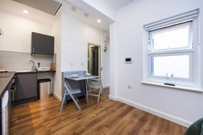 Eine kompakte Küche mit modernen Geräten, ein Essbereich mit klappbarem Tisch und ein Fenster mit Blick.