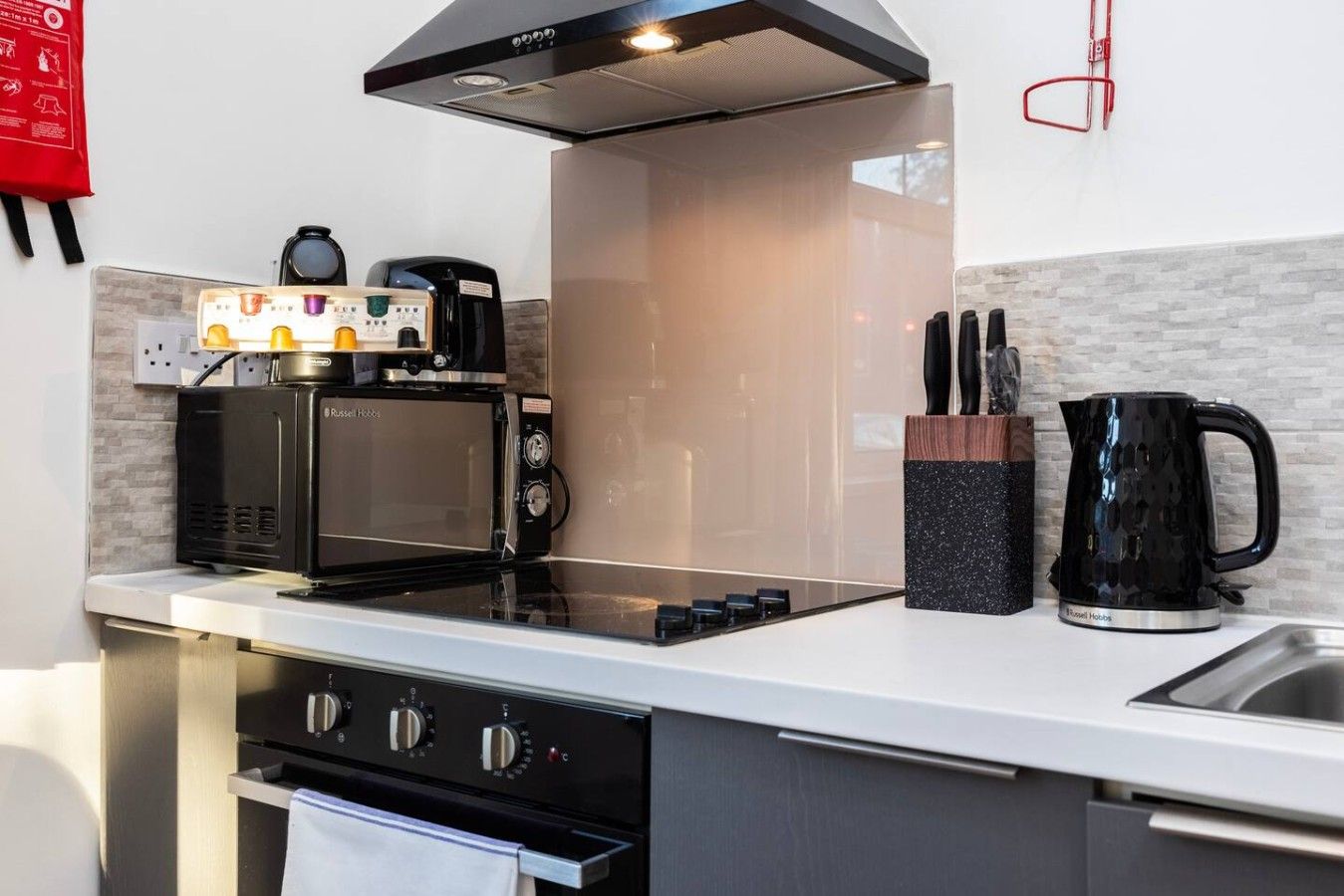 A modern kitchen with a built-in microwave, coffee maker, and kettle on the countertop.