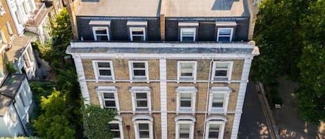 Un edificio de varios pisos con acceso en esquina, junto a una calle con flechas direccionales.
