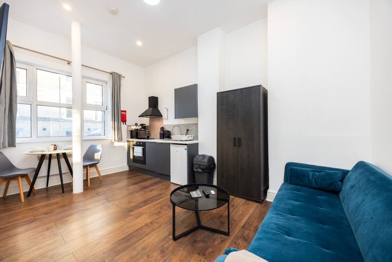 A modern living room with a blue sofa, a coffee table, and a dining area with a table and chairs.