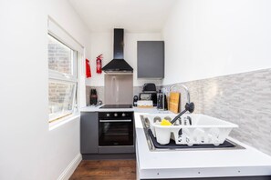 A compact kitchen with a stove, oven, sink, and a window. - Earl`s Court Residence | Elegant Studio | London (Greater London)