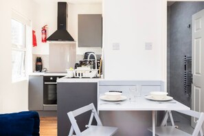 Una cocina moderna con una isla central, un comedor con mesa y sillas, y una puerta gris.