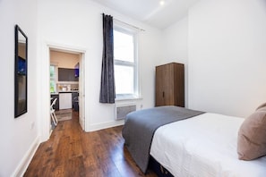 A bedroom with a bed, a wardrobe, and a window with curtains. - Earl`s Court Residence | Stylish 1BR | London (Greater London)