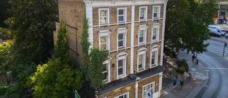 Un edificio de varios pisos con fachada de ladrillo, ventanas amplias y ubicación en esquina con acera.