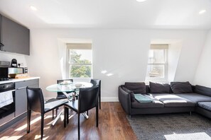 A modern living space with a dining area, a sofa, and a kitchen. - Earl`s Court Residence | Elegant 2BR | London (Greater London)