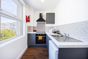 A compact kitchen with a built-in oven, a microwave, and a sink. - Earl`s Court Residence | Stylish Studio | London (Greater London)