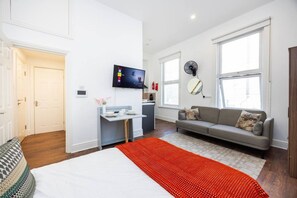 Une chambre d’hôtel moderne équipée d’un lit, d’un canapé, d’un petit coin repas et d’une télévision.