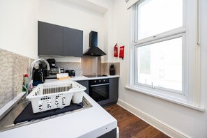 A modern kitchen with a dishwasher, oven, and a window with a view. - Earl`s Court Residence | Elegant Studio | London (Greater London)