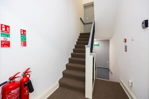 Un escalier équipé d’extincteurs et de panneaux indiquant les issues de secours.