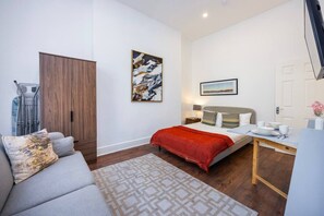 A modern bedroom with a bed, bedside table, and a desk with chairs. - Earl`s Court Residence | Elegant Studio | London (Greater London)