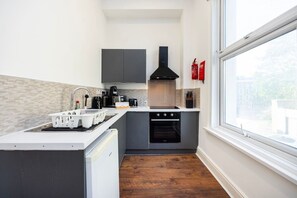 Une cuisine compacte équipée d’un four encastré, d’un évier et d’une fenêtre donnant sur l’extérieur.