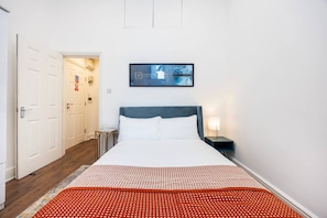A hotel room with a bed, a nightstand, a lamp, and a painting on the wall. - Earl`s Court Residence | Elegant 1BR | London (Greater London)