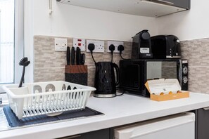 A kitchen with a coffee maker, toaster, and a basket of muffins. - Earl`s Court Residence | Elegant 1BR | London (Greater London)