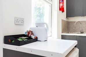 A kitchen with a coffee bar, a coffee maker, and a window with a view of trees. - Earl`s Court Residence | Stylish Studio | London (Greater London)