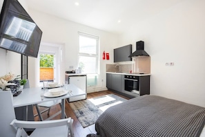 A compact hotel room with a kitchenette, a dining area, and a bed. - Earl`s Court Residence | Stylish Studio | London (Greater London)