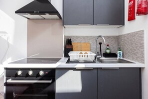 A kitchen with a stove, oven, sink, and cabinets. - Earl`s Court Residence | Elegant Studio | London (Greater London)
