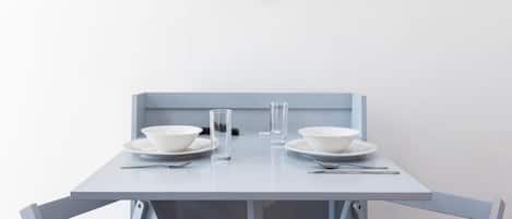 Une table à manger au design minimaliste, agrémentée de deux bols blancs, deux assiettes et deux verres.