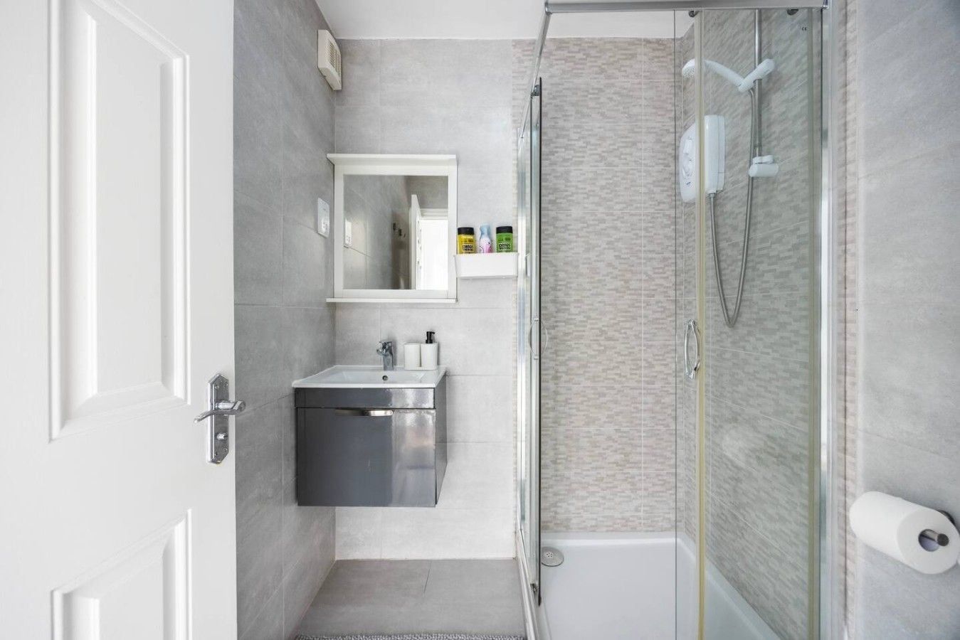 A modern bathroom with a glass shower enclosure, a sink with a mirror, and a toilet.