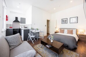 Una moderna camera d'albergo con un letto, un divano, una scrivania, angolo cottura e bagno.