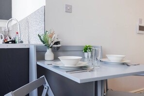 Une cuisine moderne avec un plan de travail gris, des bols blancs, un vase contenant des fleurs séchées et une petite plante en pot.
