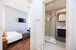Une chambre à coucher avec un lit, une télévision et une table de chevet en bois.