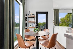 A modern dining area with a round table and leather chairs, a bookshelf, and a view of a body of water. - Riverview Luxury Condo with Garage, Balcony, Downtown (Nashville)