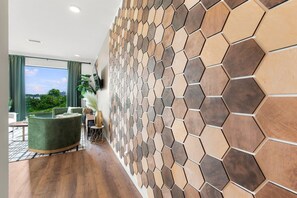 A modern interior with a hexagonal patterned wall, a reception desk, and a view of greenery outside. - Riverview Luxury Condo with Garage, Balcony, Downtown (Nashville)