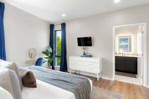 Une chambre à coucher moderne, équipée d’un lit, d’une table de chevet, d’un téléviseur et offrant une vue sur l’extérieur.