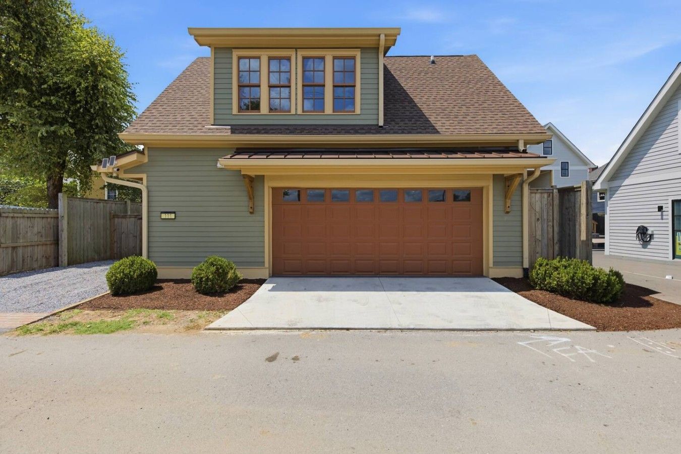 Une maison à deux étages avec un garage, un petit porche et une pelouse bien entretenue.