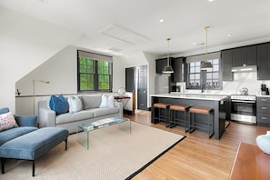 A modern kitchen with a central island, dark cabinetry, and stainless steel appliances.